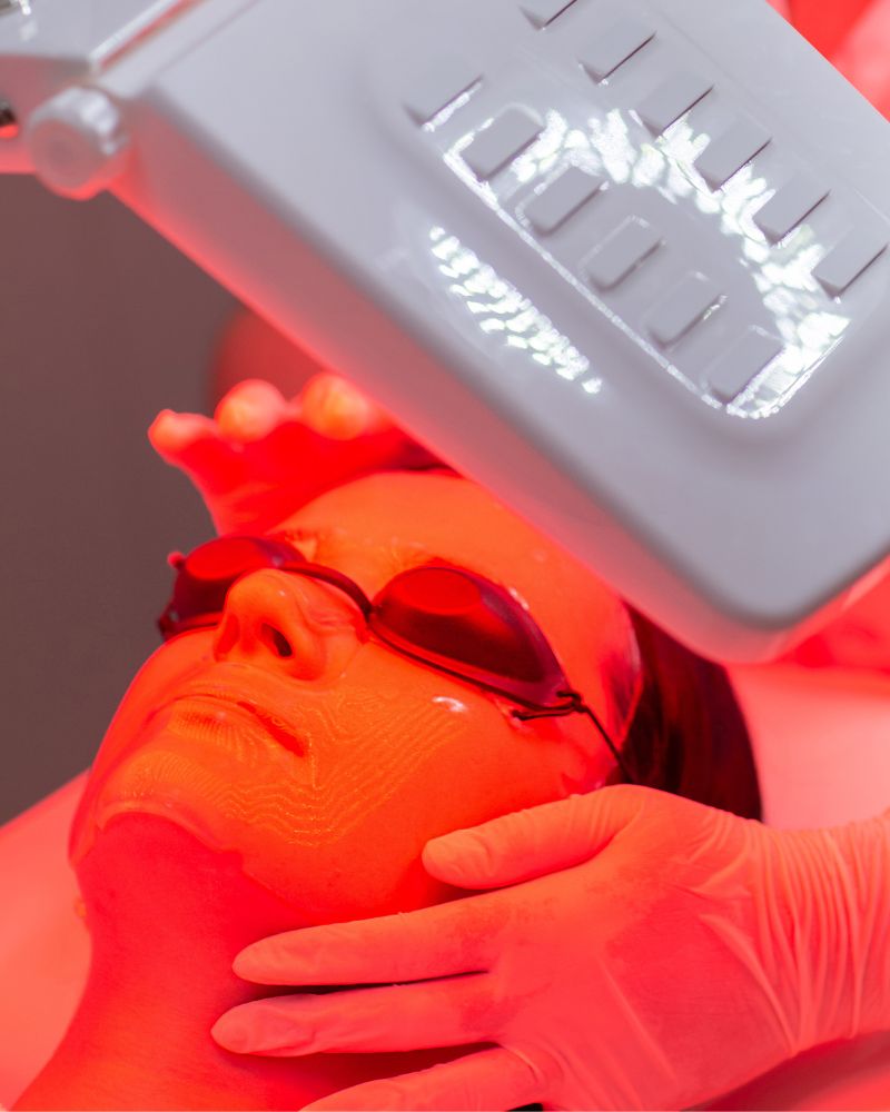 Client laying under Red light LED skin therapy with eye protection