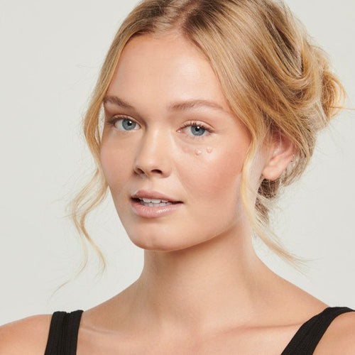 Lifestyle image of woman with colorescience total eye 3-in-1 renewal therapy spf 35 product on undereye area